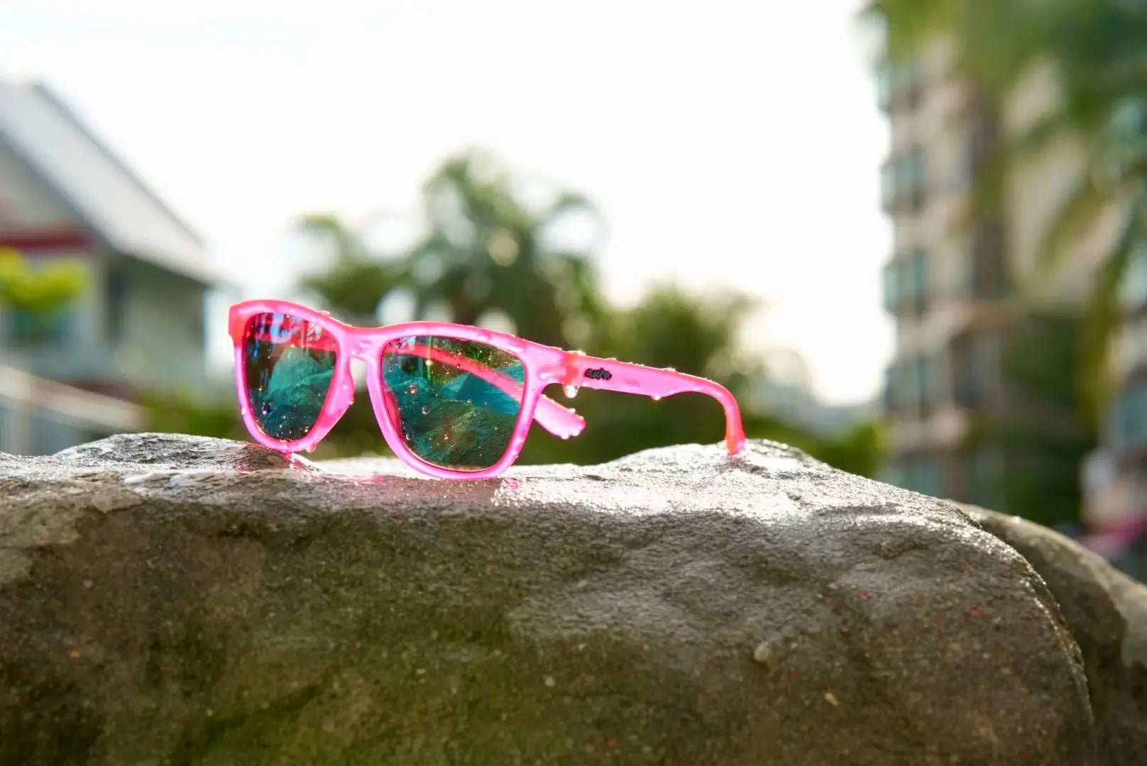 Pink polarized sunglasses with blue lenses on a rock outdoors in sunlight