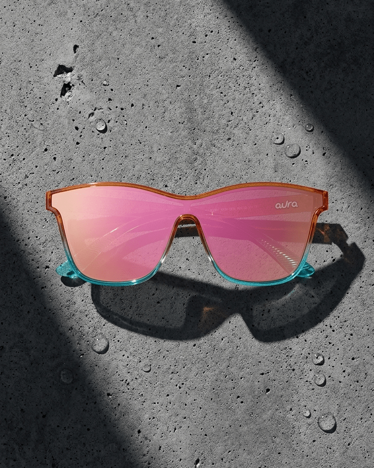 Sunglasses with red lenses and orange colorful frame on a textured black surface