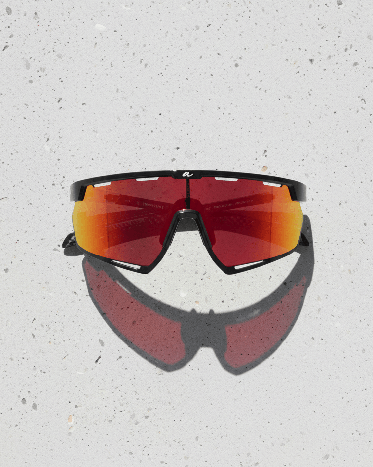 Sunglasses with red-tinted lenses on a light gray surface