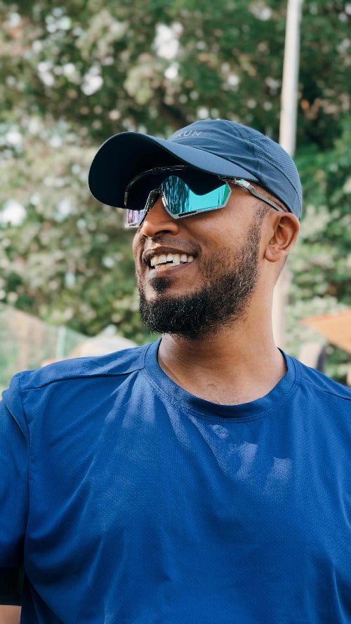 Man wearing a blue cap and sunglasses with a blurred natural background